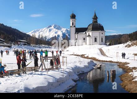 Seefeld, Tirol, Autriche - 8 mars 2020 : ski de fond sur une piste ensoleillée le long d'une rivière et d'une église pitoresque Banque D'Images