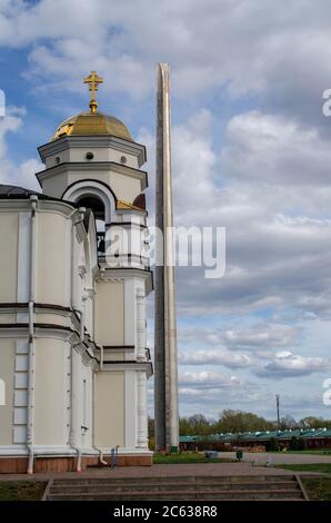 Brest, Bélarus - 18 avril 2020 : l'obélisque de la forteresse de Brest sur fond d'église orthodoxe et de ciel nuageux. Banque D'Images