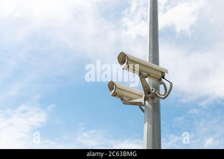 Caméras de sécurité sur un poteau en béton contre le ciel bleu. Photo de haute qualité Banque D'Images