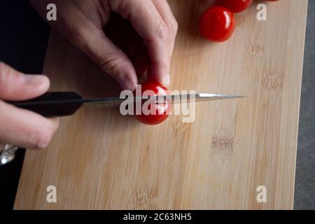 Vue rapprochée d'une personne qui coupe des tomates avec un chef couteau Banque D'Images