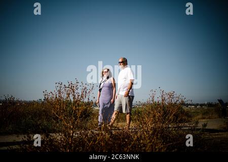 Baby Boomer couple souriant et marchant le long de Sand Dunes Banque D'Images