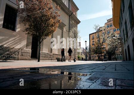 Vue arrière à angle bas des femelles méconnaissables marchant le long de la rue avec des bâtiments en pierre le jour ensoleillé à Madrid Banque D'Images