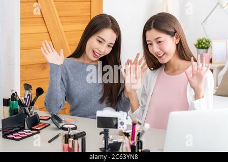 Les influenceurs de beauté de jolies petites amies asiatiques agitant les mains du public tout en enregistrant des vidéos virales avec la caméra à la maison Banque D'Images