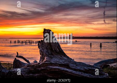 Phare de la rivière Coquille vu de l'autre côté de la rivière au crépuscule avec du bois flotté Banque D'Images