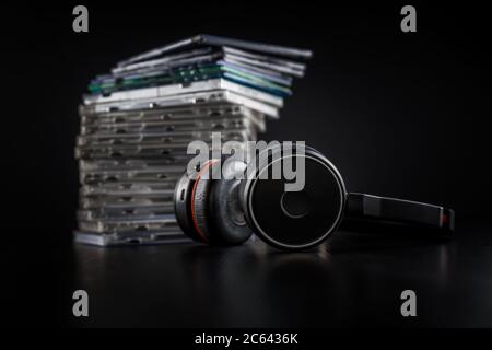 Casque hi-Fi sur pile de CD sur fond noir avec espace de copie. Banque D'Images