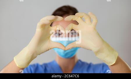 Une infirmière ou un médecin forme un cœur devant ses yeux avec ses doigts et ses mains dans des gants en latex. Banque D'Images