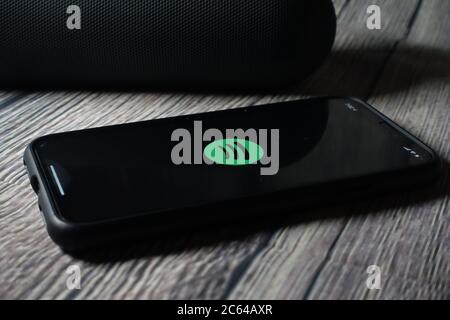 Un écran iphone 11 affichant l'icône spotify avec le haut-parleur Beats Pill à côté Banque D'Images