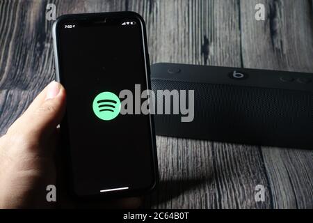 Un écran iphone 11 affichant l'icône spotify avec le haut-parleur Beats Pill à côté Banque D'Images