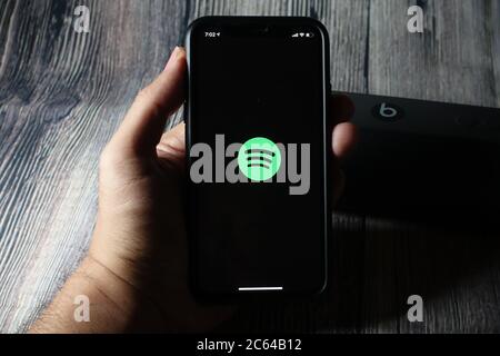 Un écran iphone 11 affichant l'icône spotify avec le haut-parleur Beats Pill à côté Banque D'Images