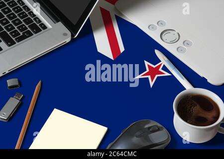 Drapeau national néo-zélandais sur l'espace de travail de créateur avec ordinateur portable, clavier d'ordinateur, clé usb, tablette graphique, tasse de café, souris Banque D'Images