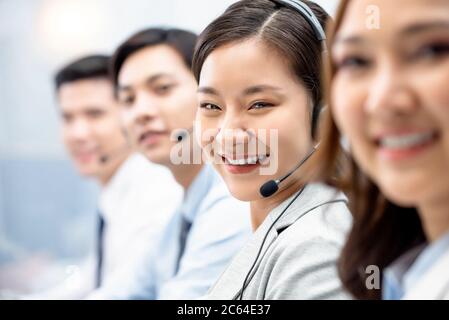 Souriante femme asiatique souriante travaillant dans le bureau du centre d'appels avec l'équipe comme opérateurs de service à la clientèle Banque D'Images