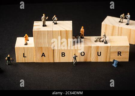 Miniature Builder Figure avec blocs de bois et libellés “TRAVAIL”. Concept de la fête du travail Banque D'Images