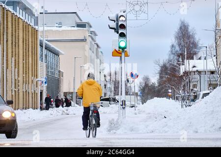 Un cycliste traverse une intersection, le feu vert est allumé, la rue enneigée de Joensuu, Finlande. Banque D'Images