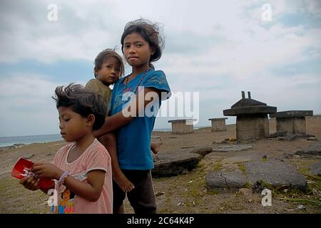 Enfants d'âge scolaire prenant soin d'un bébé dans le village de Ratenggaro, île de Sumba, province de Nusa Tenggara est, Indonésie. © Reynold Sumayku Banque D'Images