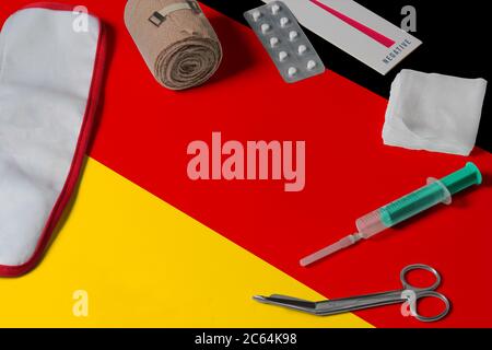 Drapeau allemand avec kit médical de premiers soins sur fond de table en bois. Concept de système de santé national, thème médical. Banque D'Images