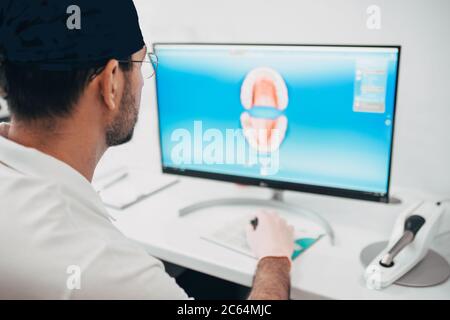 Le dentiste prosthétiste simule une mâchoire humaine sur le moniteur pour la fabrication de prothèses Banque D'Images