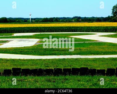 piste de course de gocart vide en été avec des virages sur route et des pneus en caoutchouc pour la sécurité de course, terrain de maïs vert luxuriant en arrière-plan. concept d'amusement extérieur Banque D'Images