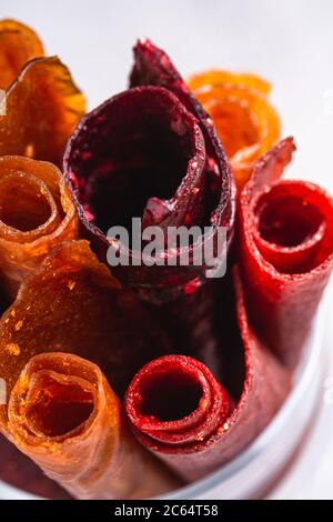 Pastille de fruits dans une tasse de verre sur fond de béton de pierre. Nourriture roulait sans sucre biologique à base de framboise, fraise, pêche et pomme. Maison végétalienne Banque D'Images