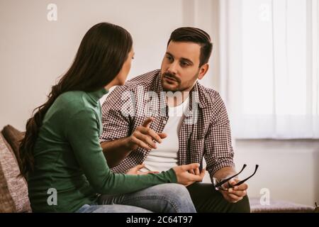 L'homme et la femme sont assis sur un canapé à la maison et parlent. Banque D'Images