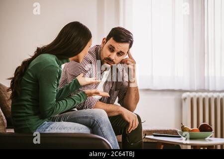 L'homme et la femme sont assis sur un canapé à la maison et parlent. Banque D'Images