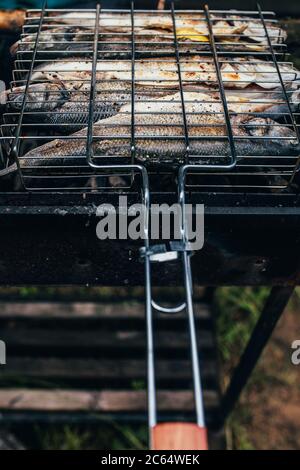 Vue de la première personne du gril sur le gril - faire frire du poisson sur des charbons chauds - cuisiner des aliments à faible teneur en calories Banque D'Images