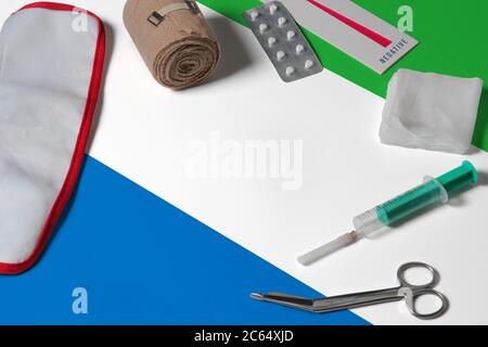 Drapeau Sierra-léonais avec trousse médicale de premiers soins sur fond de table en bois. Concept de système de santé national, thème médical. Banque D'Images