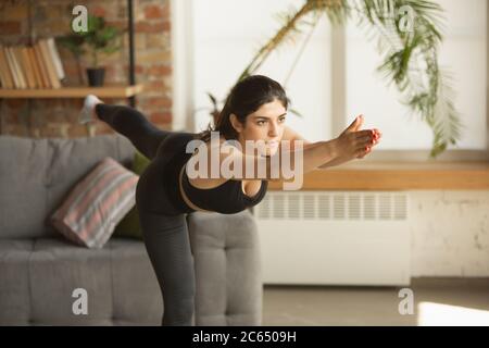 Vitalité. Sportive arabe, musulmane belle jeune femme prenant des cours de yoga professionnels en ligne et de pratiquer à la maison. Concept de mode de vie sain, bien-être, bien-être, passe-temps. Flexible et motivé. Banque D'Images