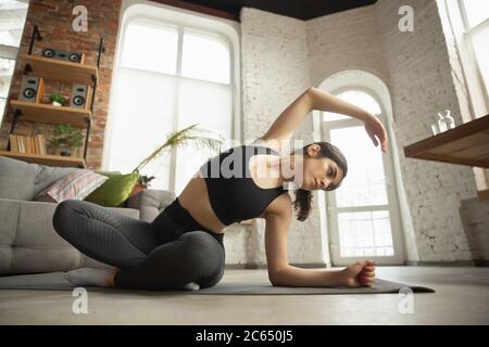 Vitalité. Sportive arabe, musulmane belle jeune femme prenant des cours de yoga professionnels en ligne et de pratiquer à la maison. Concept de mode de vie sain, bien-être, bien-être, passe-temps. Flexible et motivé. Banque D'Images