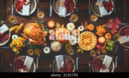 Dîner traditionnel pour la fête de Thanksgiving. dinde rôtie garnie de canneberges sur une table de style rustique ornée de citrouilles, légumes, pi Banque D'Images