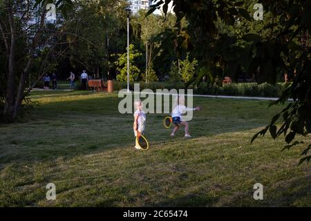 Moscou/Russie - juin 2020: Sœurs s'amusant en plein air jouant au tennis dans le parc. Fille lève raquette essayer de frapper la balle. Activités pour les enfants Banque D'Images