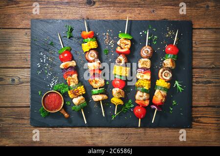 Brochettes de poulet sur brochettes avec champignons et légumes sur plaque d'ardoise Banque D'Images