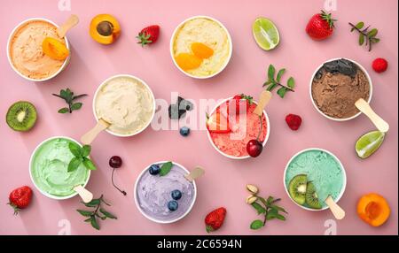 Diverses sortes de glaces colorées avec fruits dans des gobelets en papier sur fond rose Banque D'Images