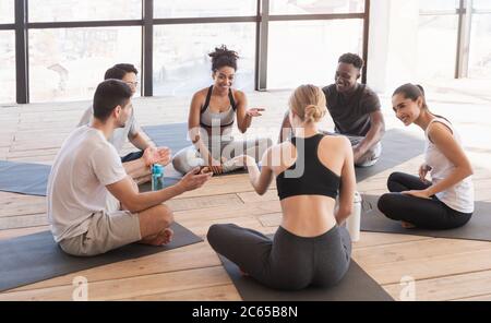 Groupe de jeunes multiethniques dans les vêtements de sport ayant le repos après la formation de yoga Banque D'Images