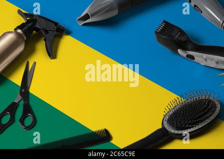 Drapeau rwandais avec outils de coupe de cheveux. Peignes, ciseaux et outils de coiffure dans un bureau de salon de beauté sur fond national en bois. Banque D'Images