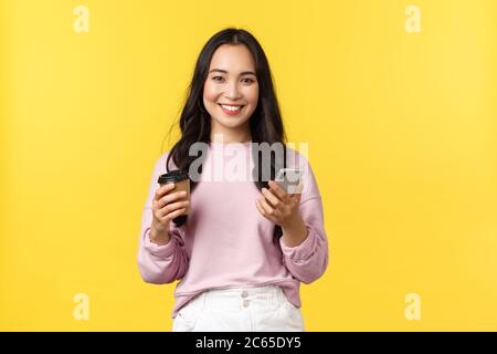 Les émotions des gens, le style de vie, les loisirs et la beauté concept. Attrayante étudiante féminine, jeune fille d'université boire un café à emporter et vérifier les messages sur Banque D'Images