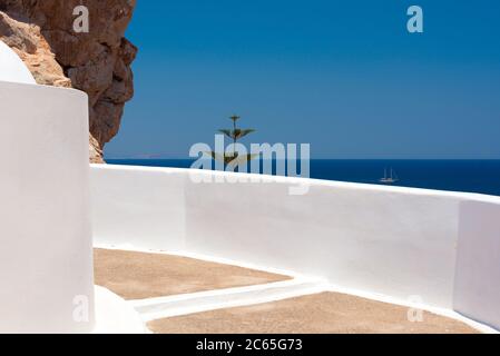 Un bateau s'étend au-delà du mur blanc de l'église Agios Ioannis, près de Monolithos, sur l'île de Santorin Banque D'Images