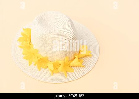 Chapeau de paille avec fleurs de nénuphars jaunes sur fond pastel. Modèle rétro élégant. Fond jaune. Concept de mode d'été. Copier l'espace. Banque D'Images