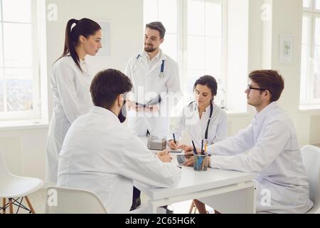 Groupe de médecins praticiens lors d'une réunion discuter du diagnostic d'un patient debout dans un bureau de clinique. Banque D'Images