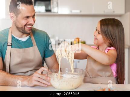 Papa et fille pétrissent de la pâte dans la cuisine à la maison Banque D'Images