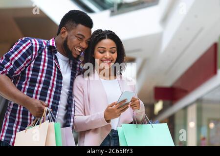 Concept de remboursement. Couple Happy Black avec smartphone. Compte bancaire après achat Banque D'Images