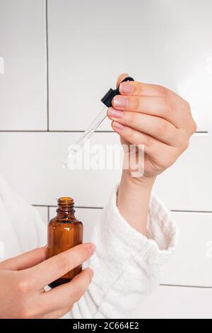 Mains féminines tenant le flacon avec du sérum, de l'huile essentielle ou autre Banque D'Images
