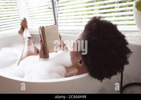 Femme lisant un livre dans une baignoire Banque D'Images