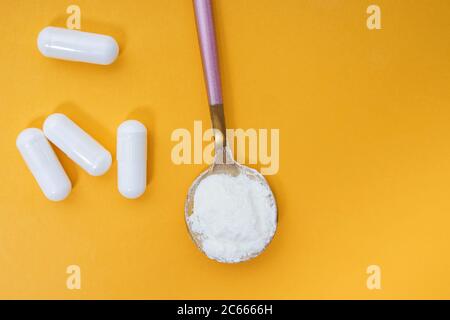 Poudre de collagène et pilules sur fond jaune Banque D'Images
