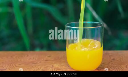 Verser la boisson fraîche au mangue biologique dans un verre transparent en plein air en été. Banque D'Images