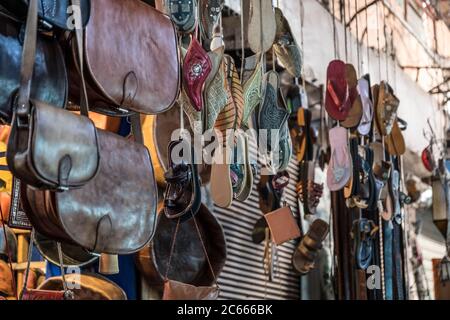 Sacs en cuir et sandales suspendus dans un souk à Marrakech, Maroc Banque D'Images