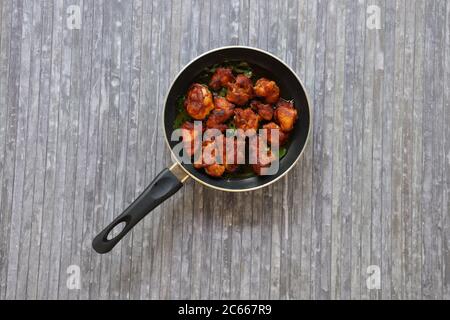 Poulet frit ou poulet frit kabab qui est bien garni de feuilles de curry dans une poêle noire avec fond gris Banque D'Images