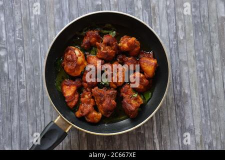 Poulet frit ou poulet frit kabab qui est bien garni de feuilles de curry dans une poêle noire avec fond gris Banque D'Images