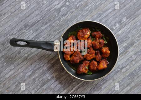 Poulet frit ou poulet frit kabab qui est bien garni de feuilles de curry dans une poêle noire avec fond gris Banque D'Images