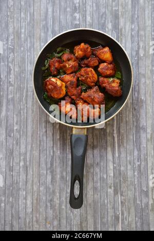Poulet frit ou poulet frit kabab qui est bien garni de feuilles de curry dans une poêle noire avec fond gris Banque D'Images