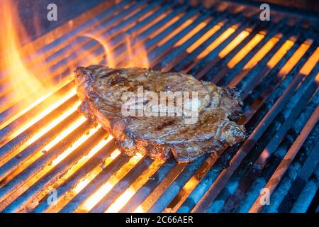 Le steak de la rivée est cuit sur un gril avec une flamme et de la fumée. Banque D'Images